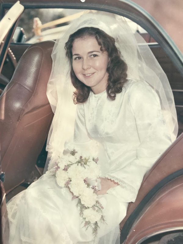 Lorraine in wedding dress sitting in back of car